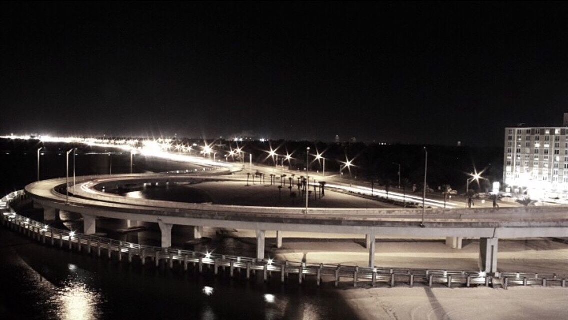 ILLUMINATED BRIDGE OVER RIVER AT NIGHT