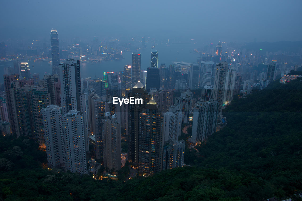High angle view of illuminated cityscape in foggy weather at dusk