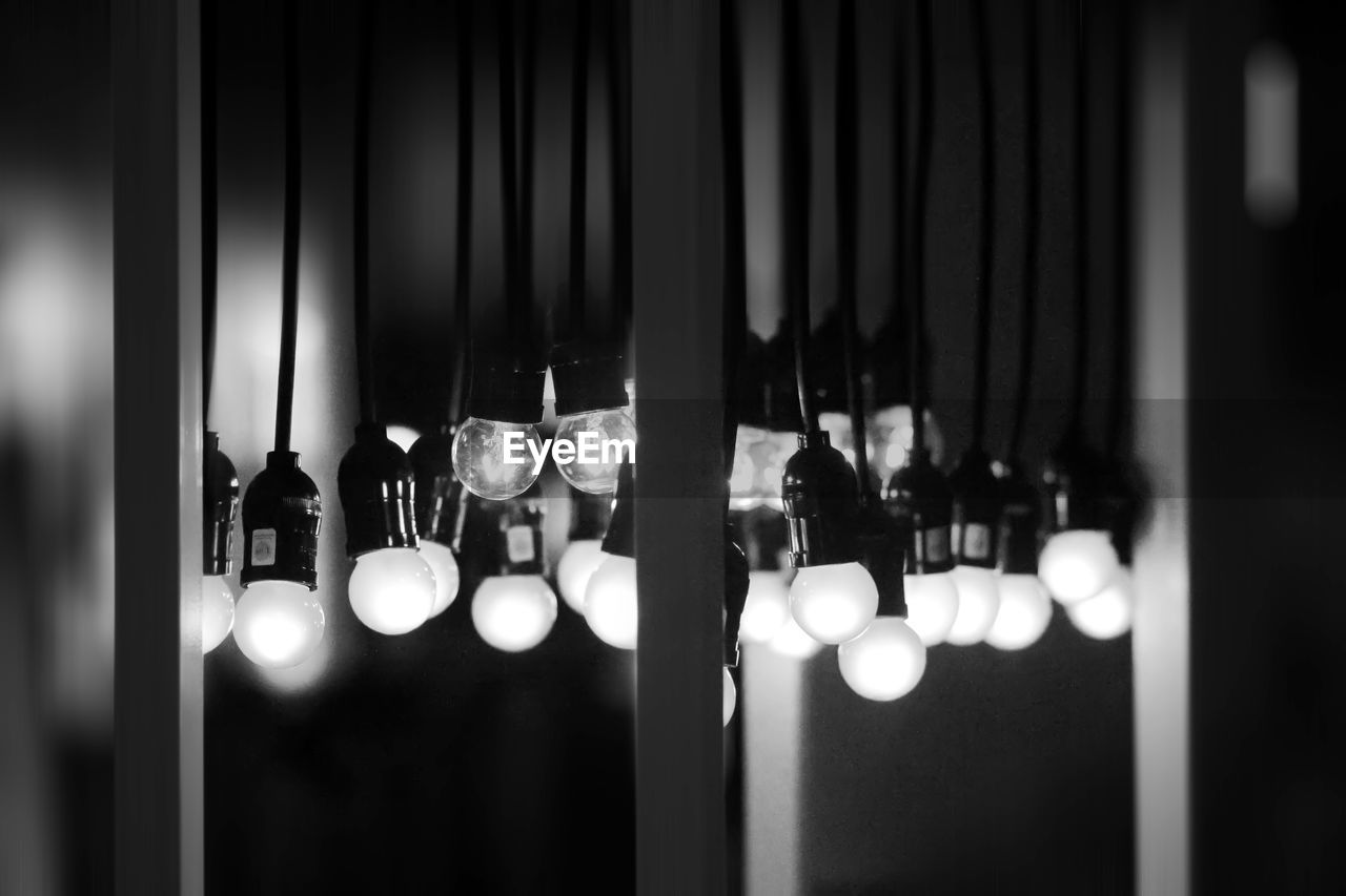 Close-up of illuminated light bulb hanging on window