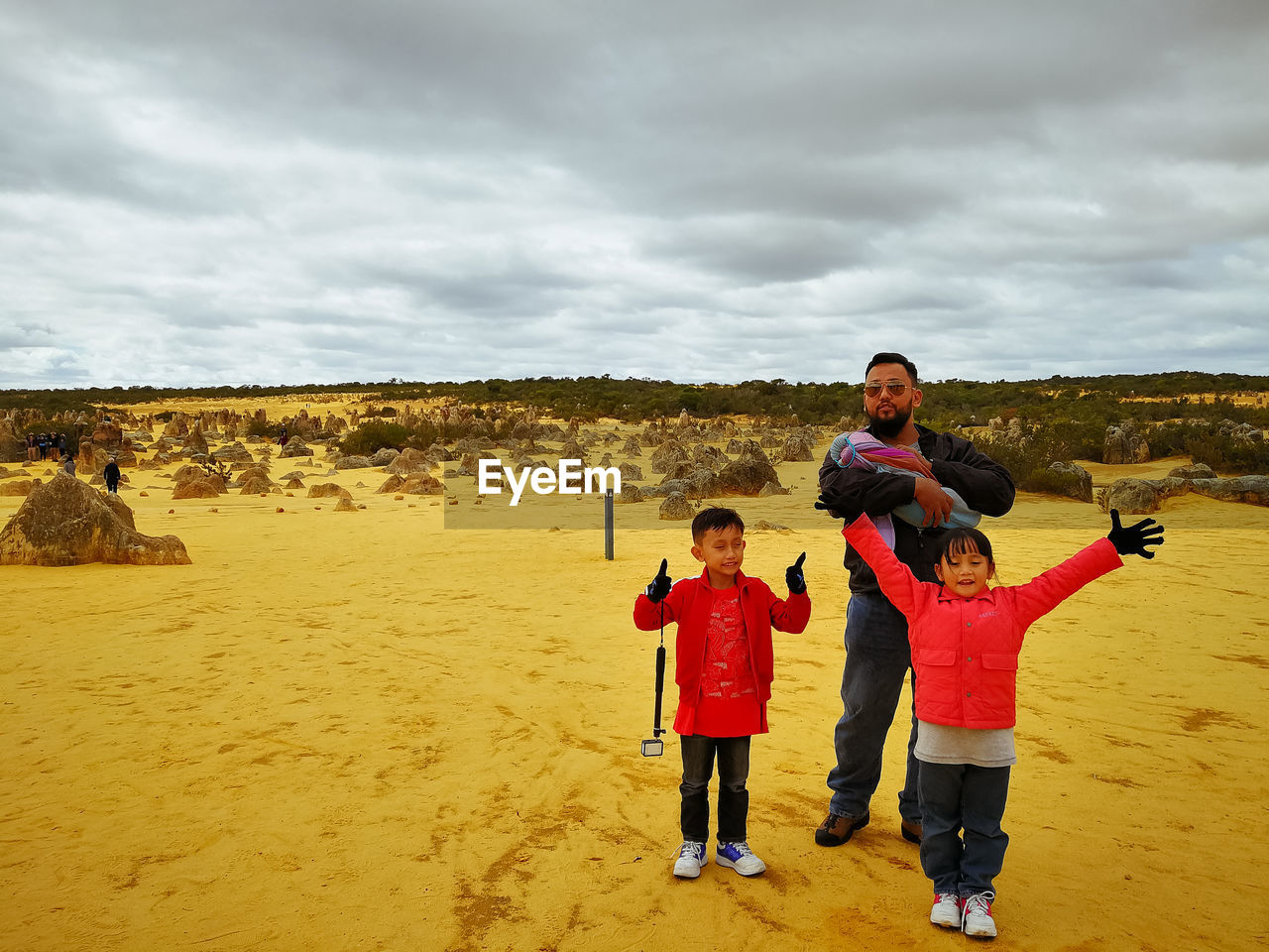 Full length of father and children standing on desert against sky