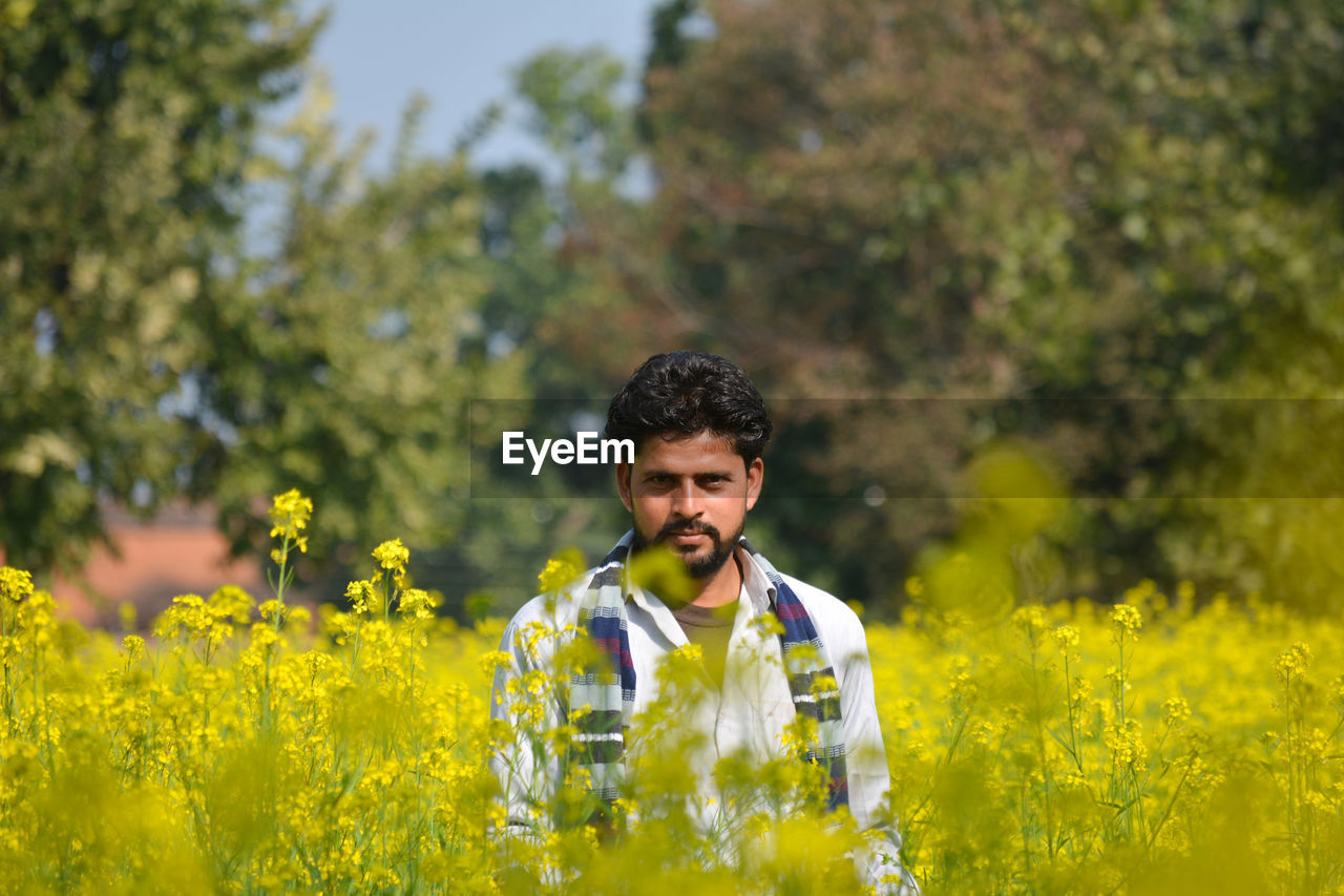 Young indian farmer at black mustard field