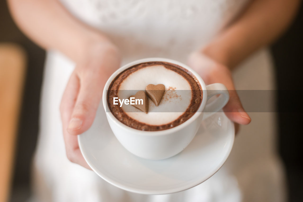 Close-up midsection woman holding coffee cup on table