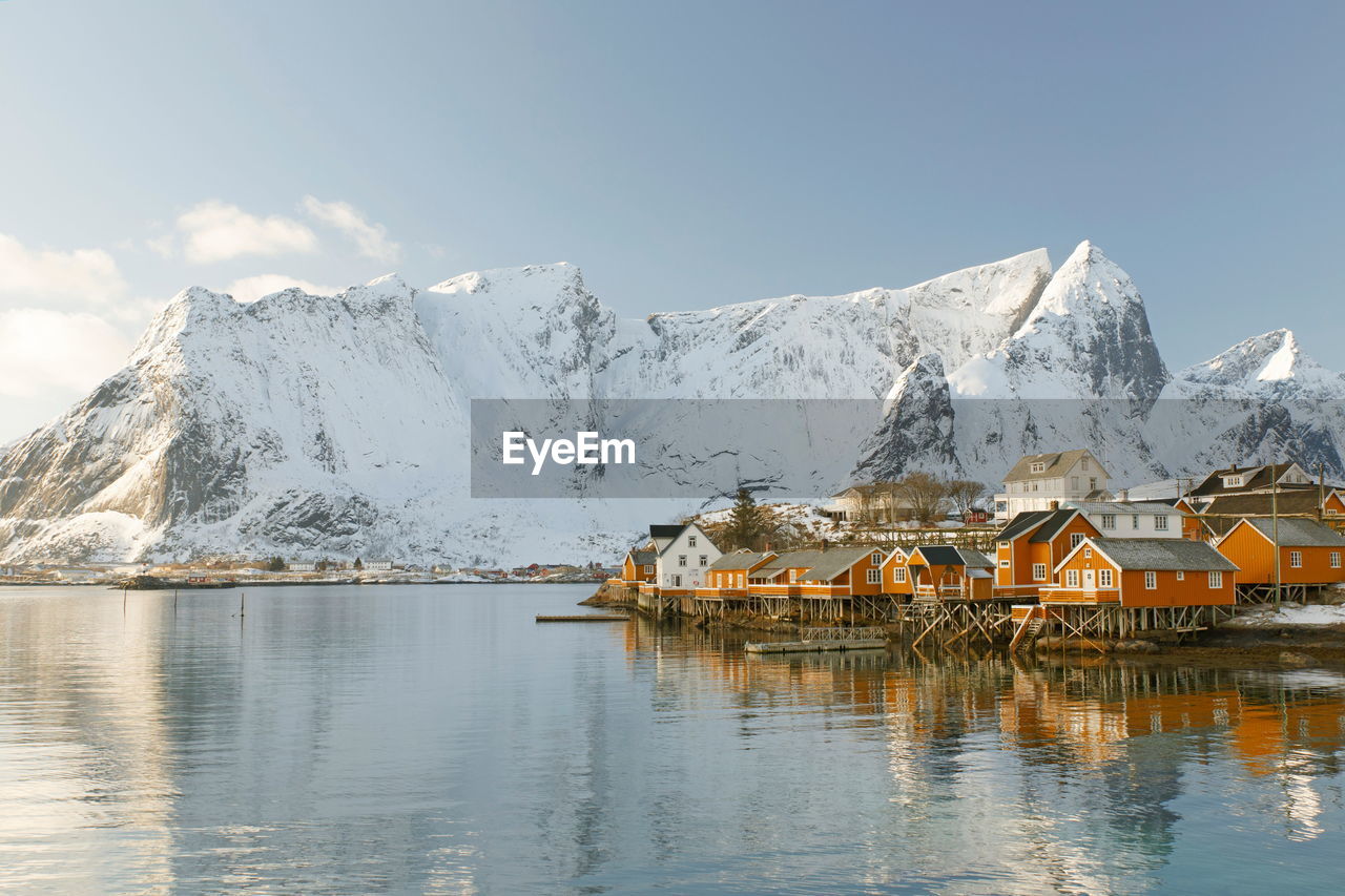 Stilt houses by lake against snowcapped mountains