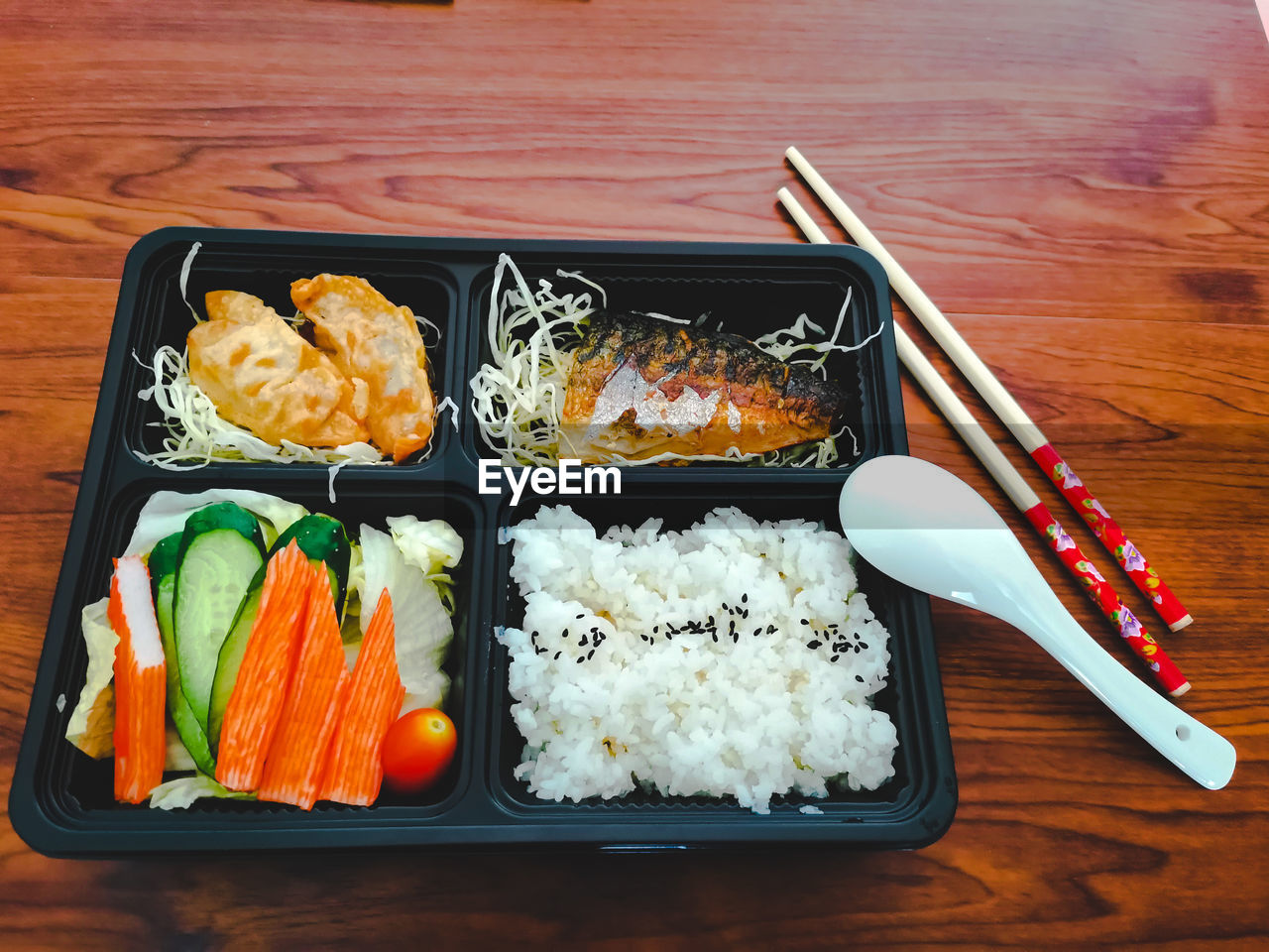 Lunch box lunch in japanese style on the wood-patterned table.