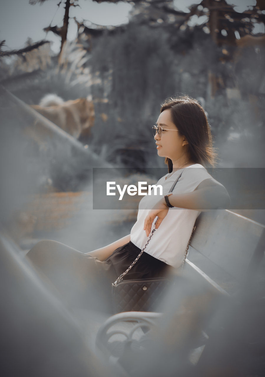 Portrait of young woman looking away while standing outdoors