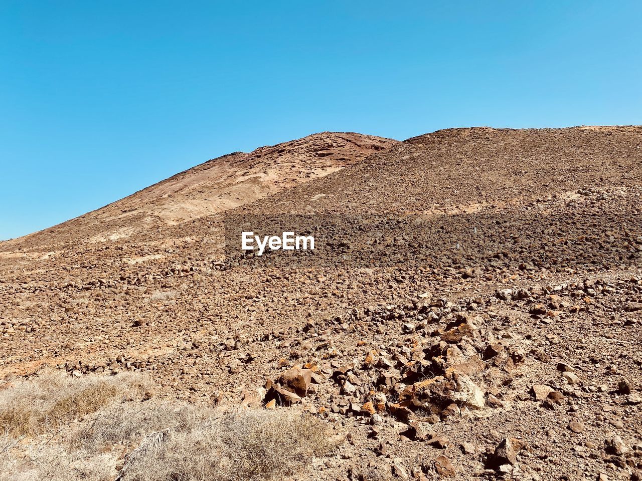 Scenic view of desert against clear blue sky