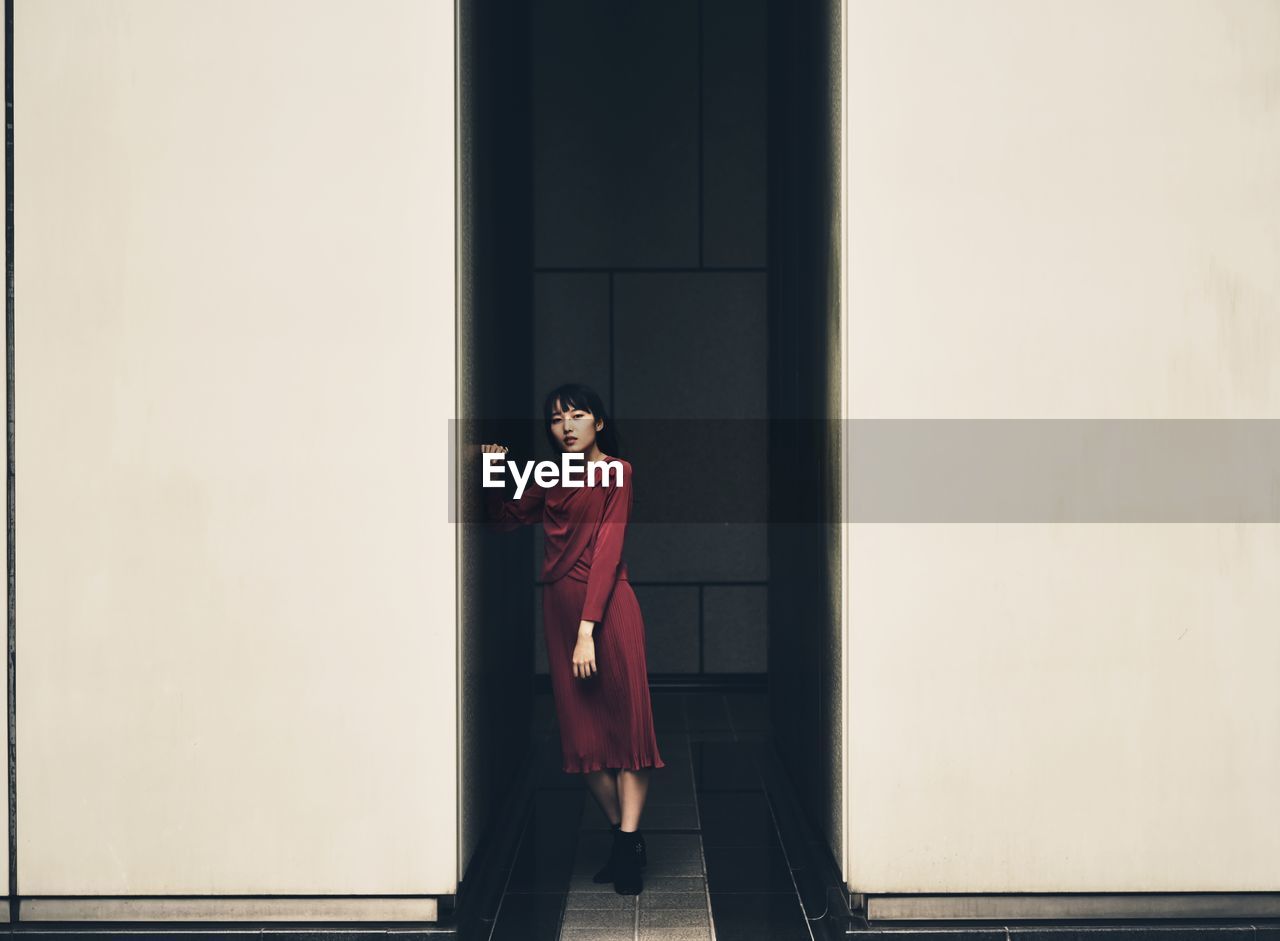 Portrait of woman standing against wall