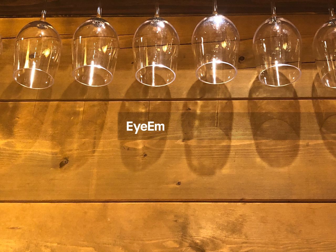 Low angle view of wineglasses hanging on wooden wall