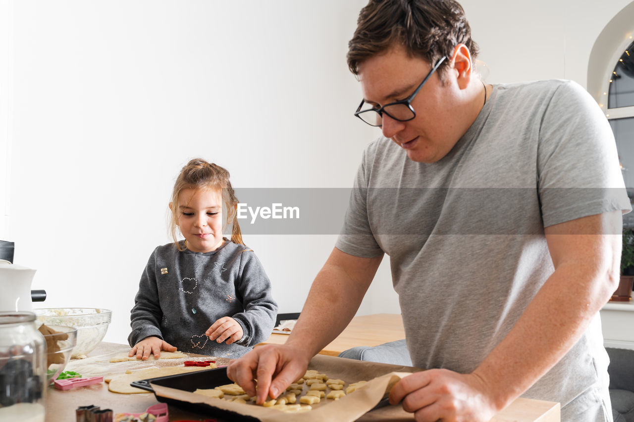 Father making cookies with daughter at home