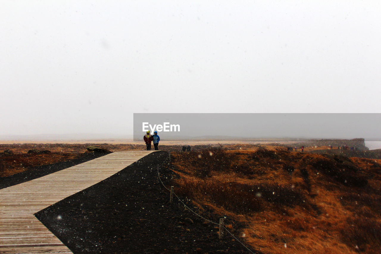 People walking on a snowy day on a bridge in iceland