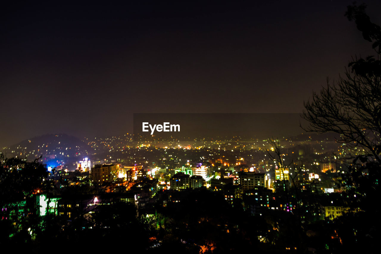 Illuminated cityscape against sky at night