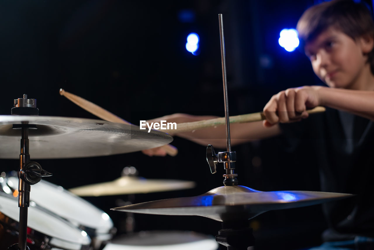 cropped image of man playing drum at night