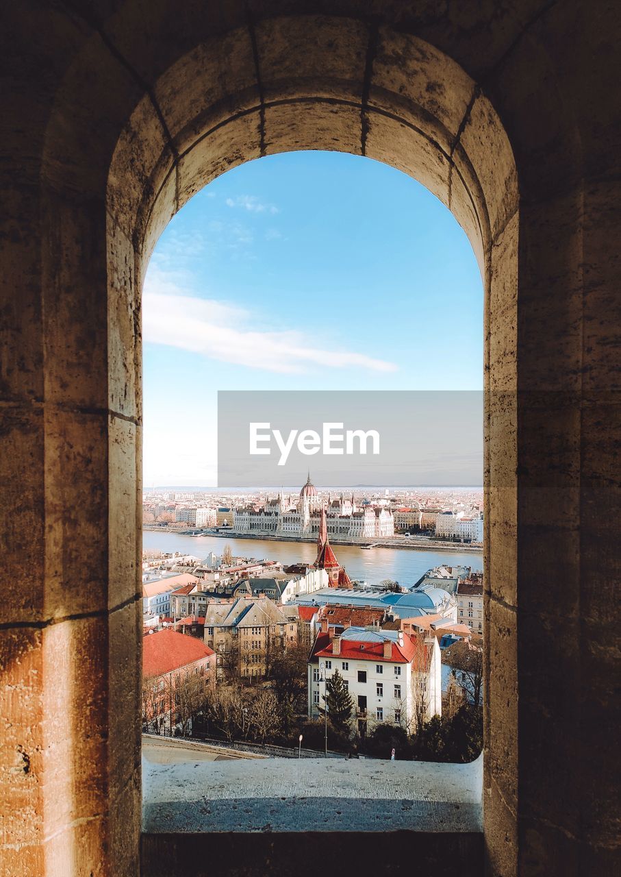 BUILDINGS AGAINST SKY SEEN FROM ARCH