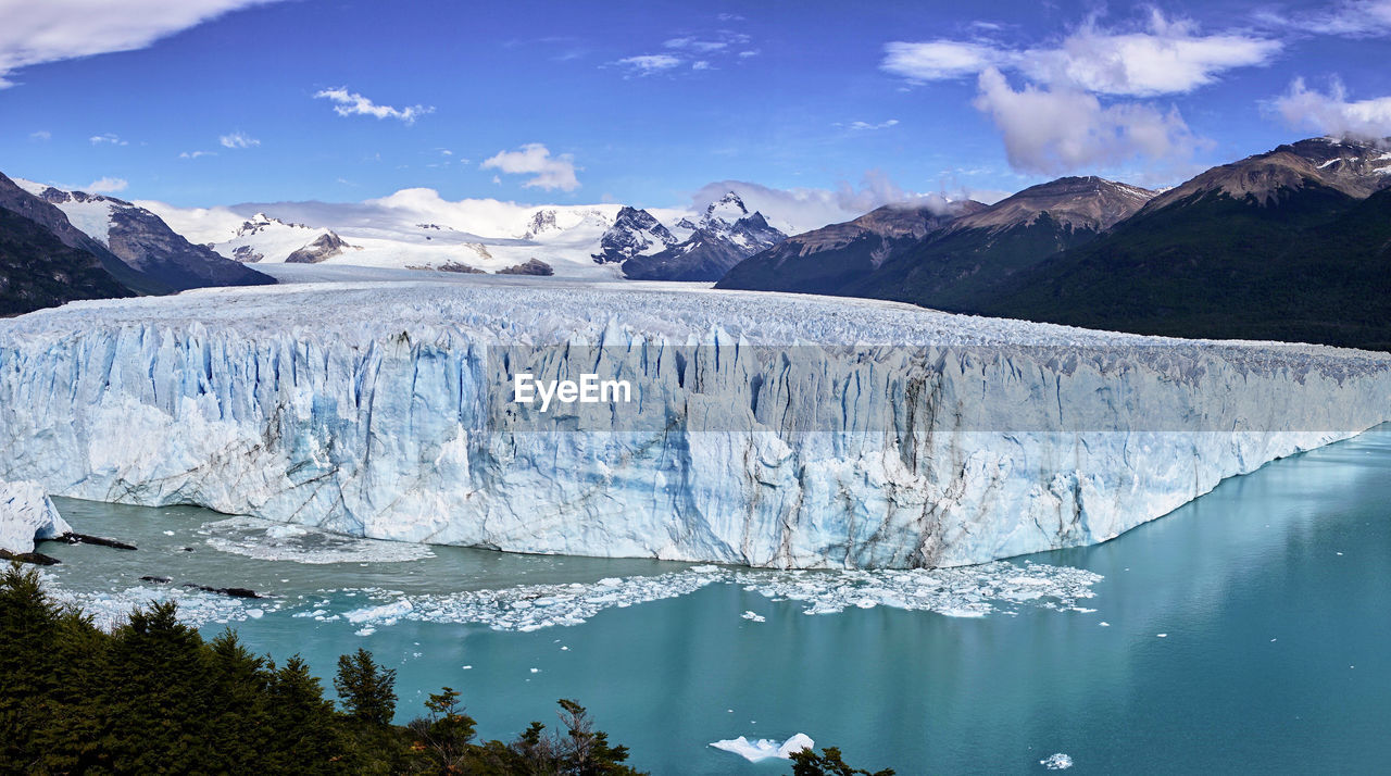 Ice bergs in sea against mountains during winter