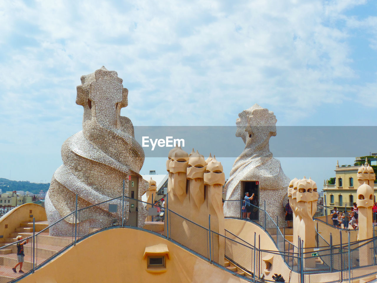 Sculptures in city against cloudy sky