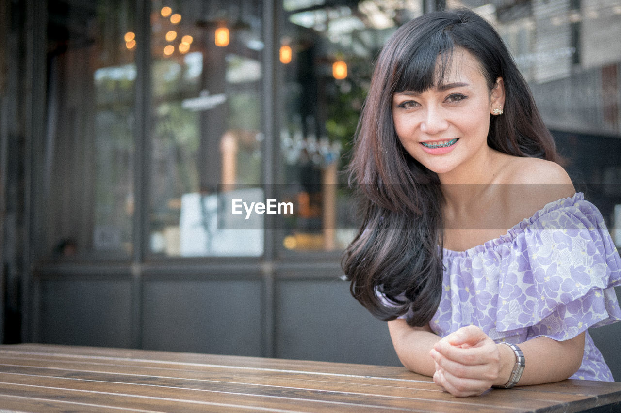 Young woman sitting on wooden table