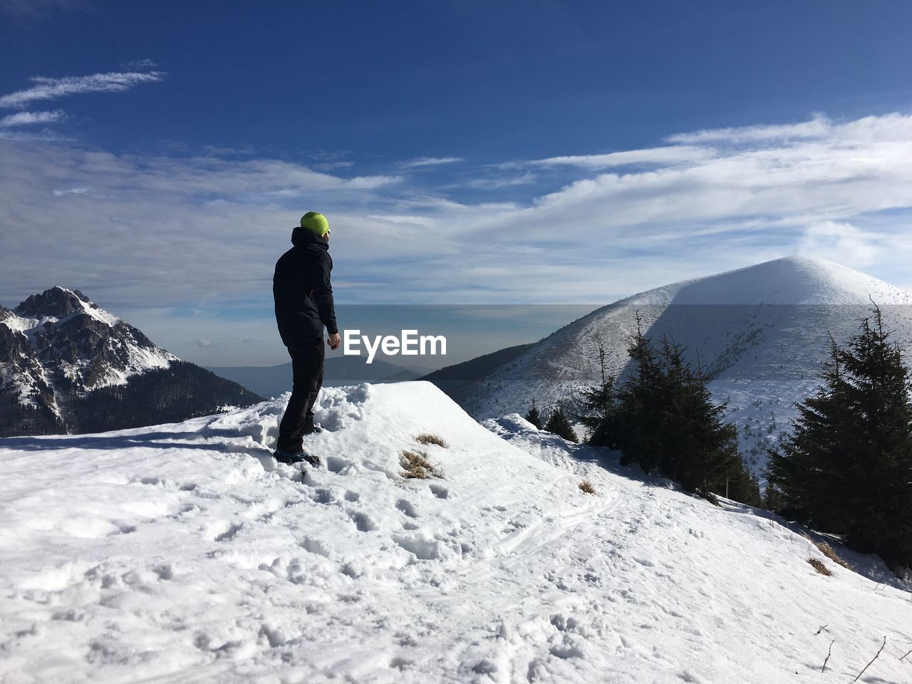 Man standing on snowcapped mountain against cloudy sky