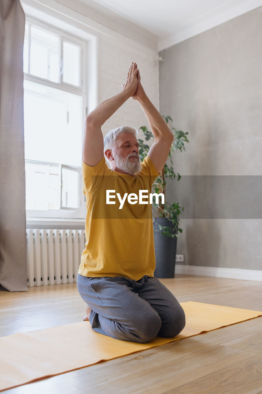 Man with gray hair meditates and does breathing exercises. sports fitness and physical exercises 