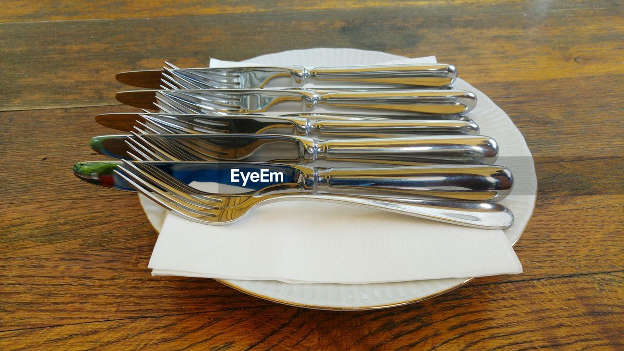Close-up of neatly arranged cutlery on wooden table