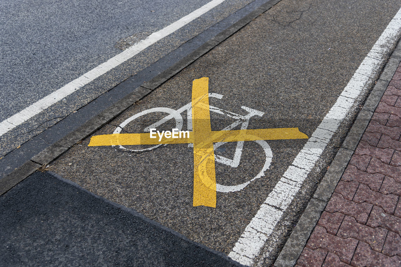 HIGH ANGLE VIEW OF YELLOW ARROW SYMBOL ON ROAD