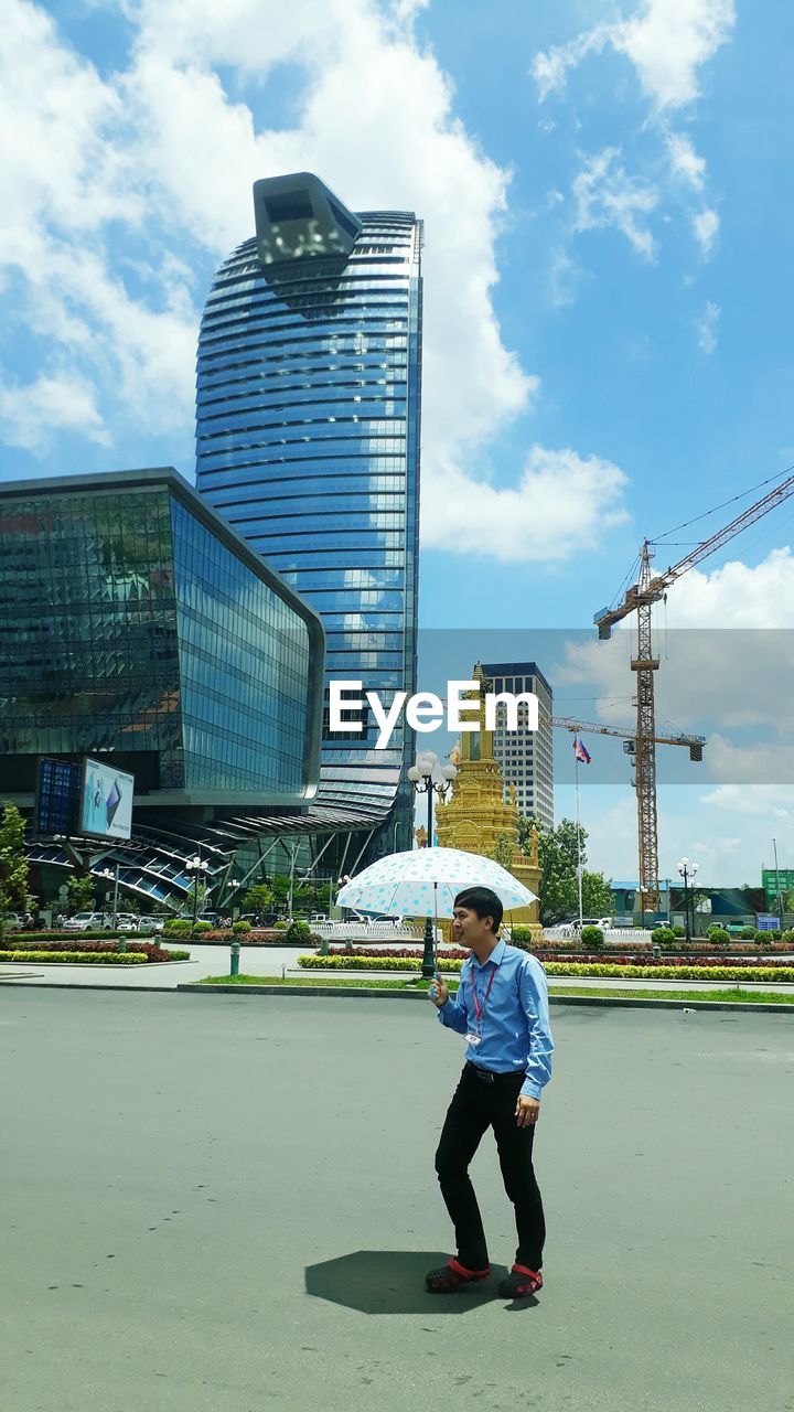 FULL LENGTH OF BOY WITH UMBRELLA AGAINST SKY