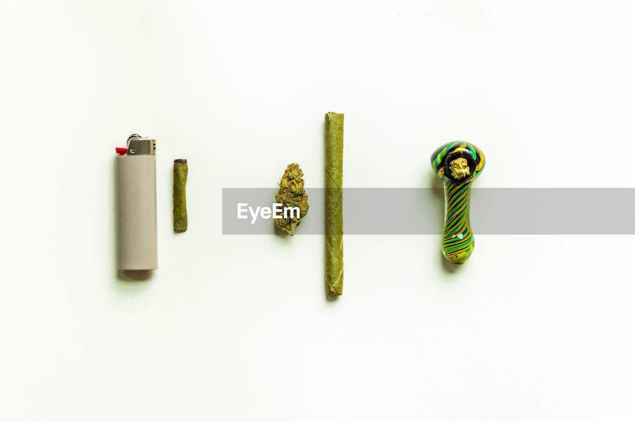 Marijuana flat lay. cannabis flower, weed roach, and smoking pipe on a white background.