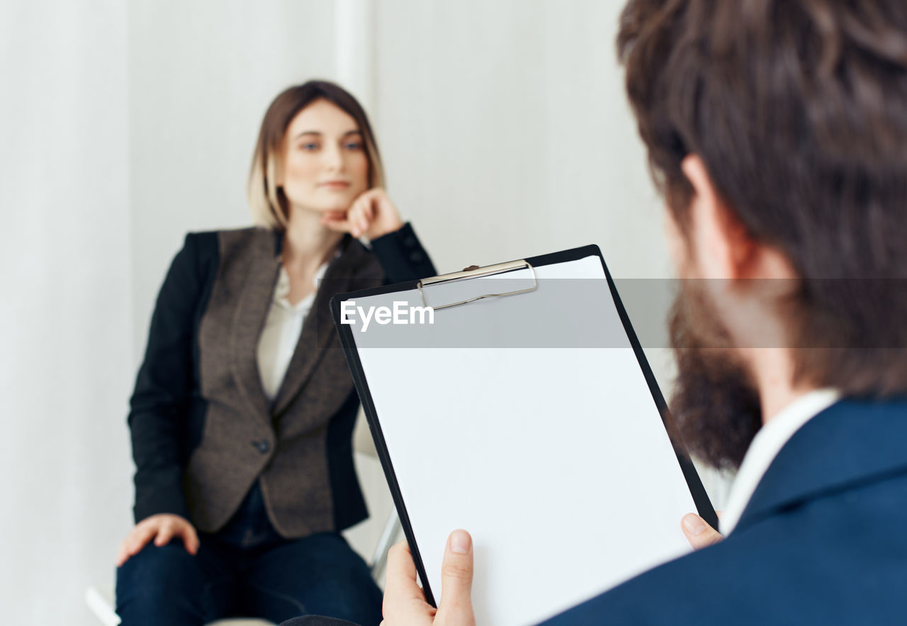 PORTRAIT OF A WOMAN USING PHONE WHILE SITTING ON LAPTOP