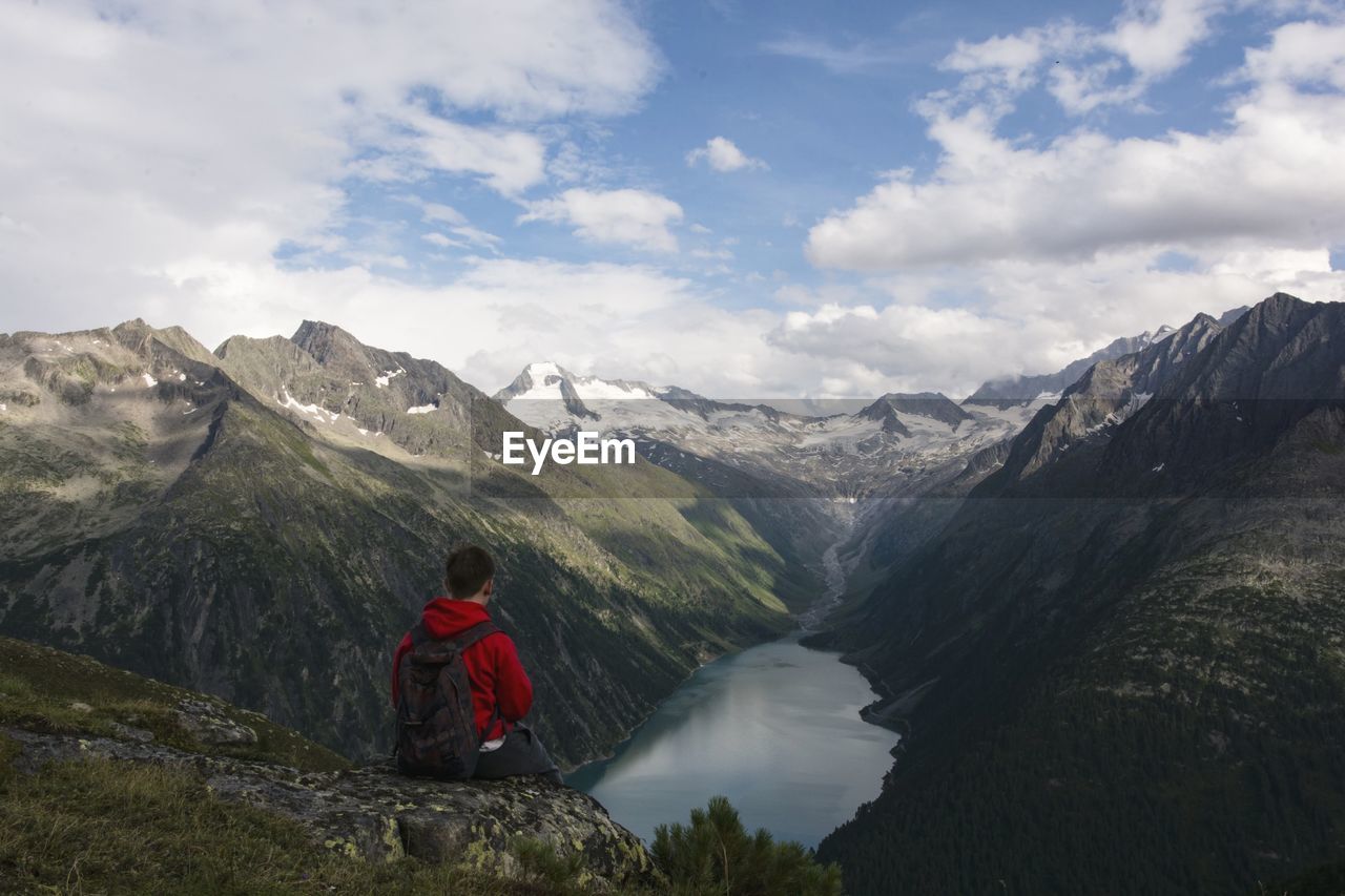 MAN LOOKING AT MOUNTAIN AGAINST SKY