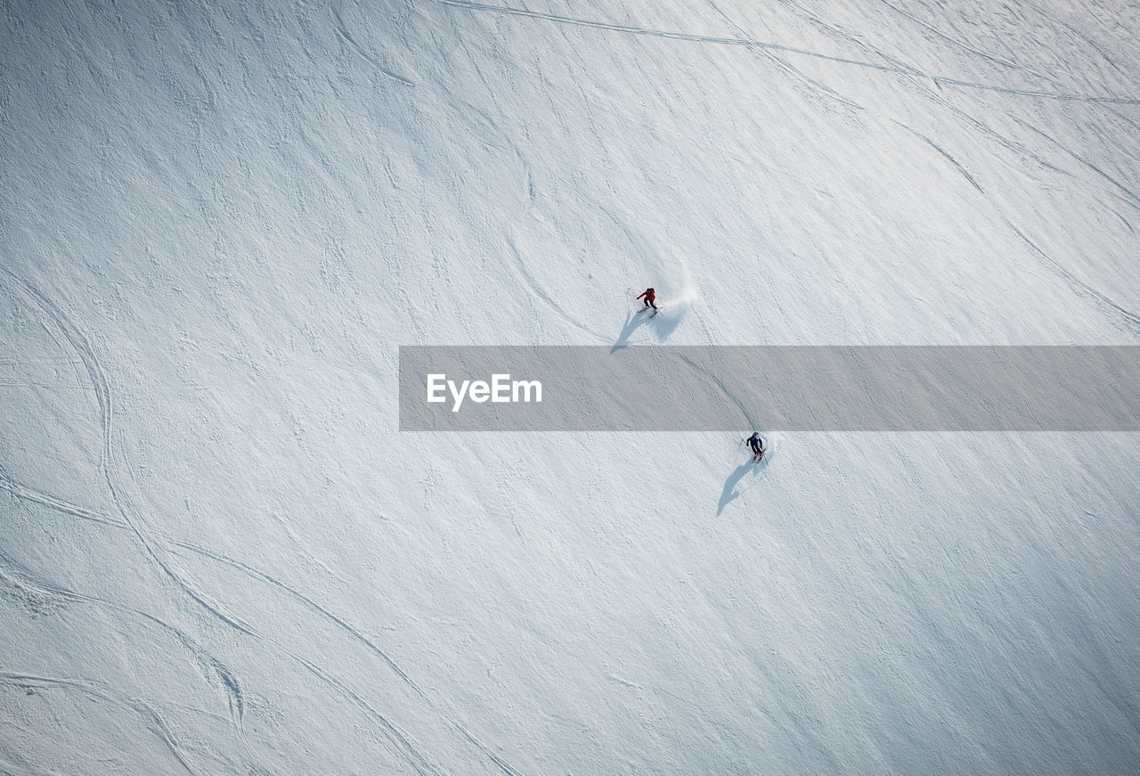 Two men skiing on snow in iceland from overhead angle