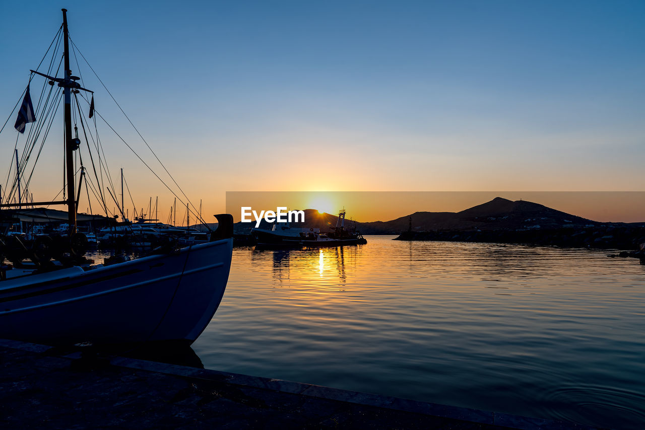 BOATS MOORED IN SEA AGAINST SKY DURING SUNSET