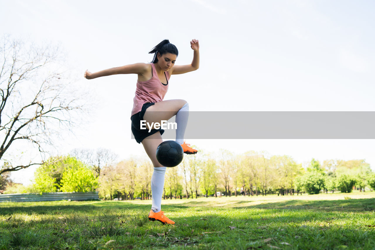 FULL LENGTH OF YOUNG WOMAN JUMPING ON FIELD