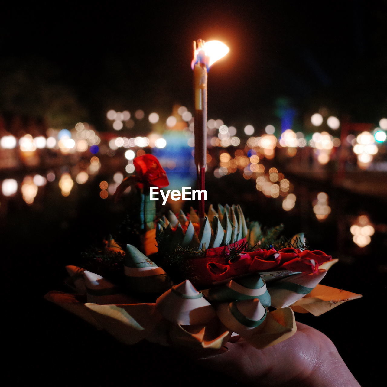 candle, illuminated, night, hand, celebration, lighting equipment, burning, nature, holding, one person, event, flame, lighting, fire, food and drink, decoration, outdoors, focus on foreground, tradition, light