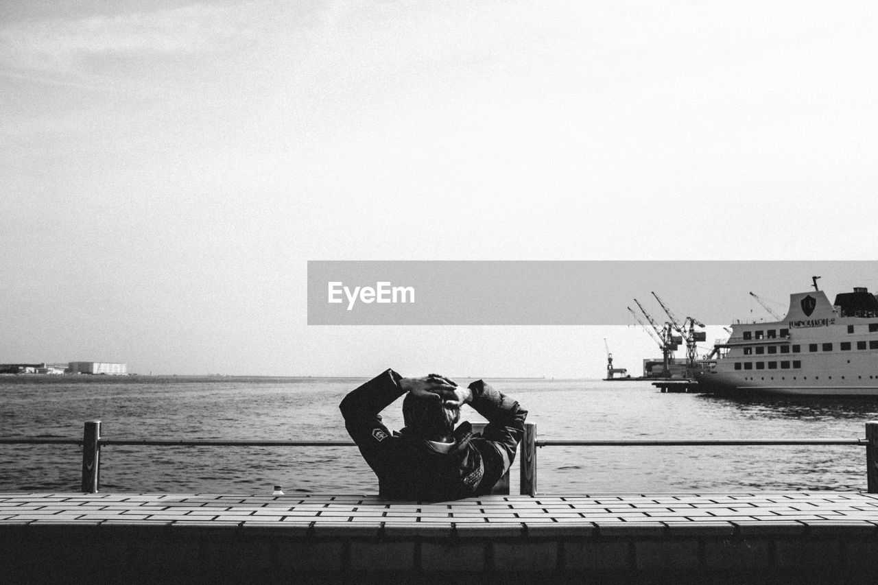 PEOPLE SITTING ON SEA AGAINST SKY