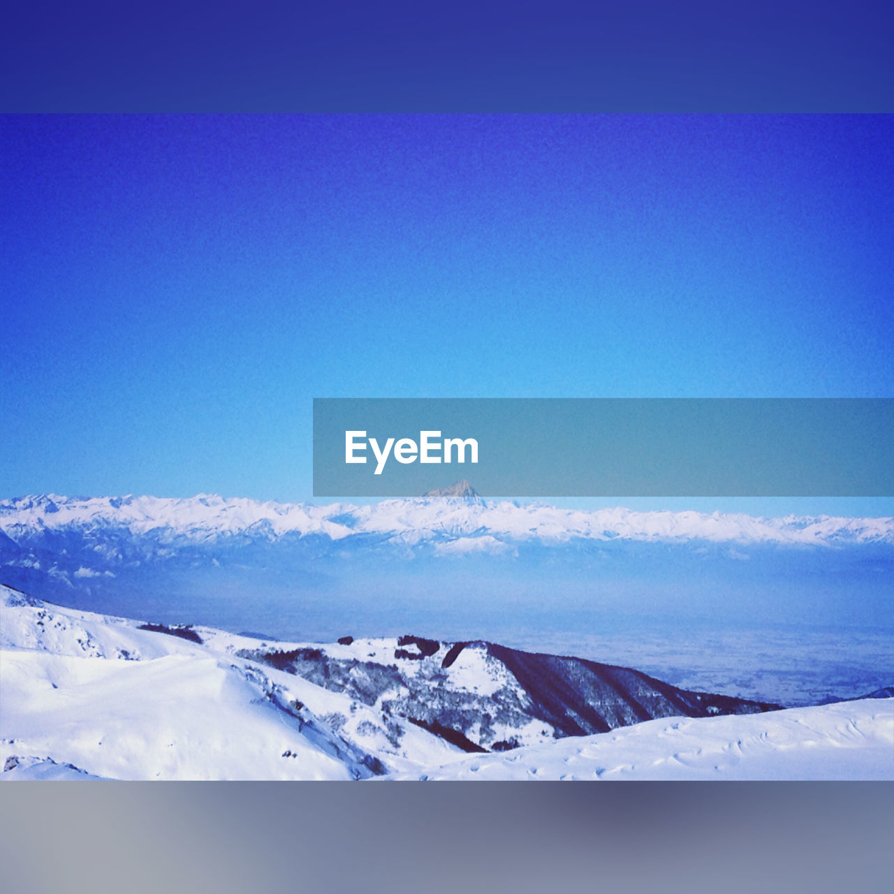 Scenic view of snowcapped mountains against blue sky