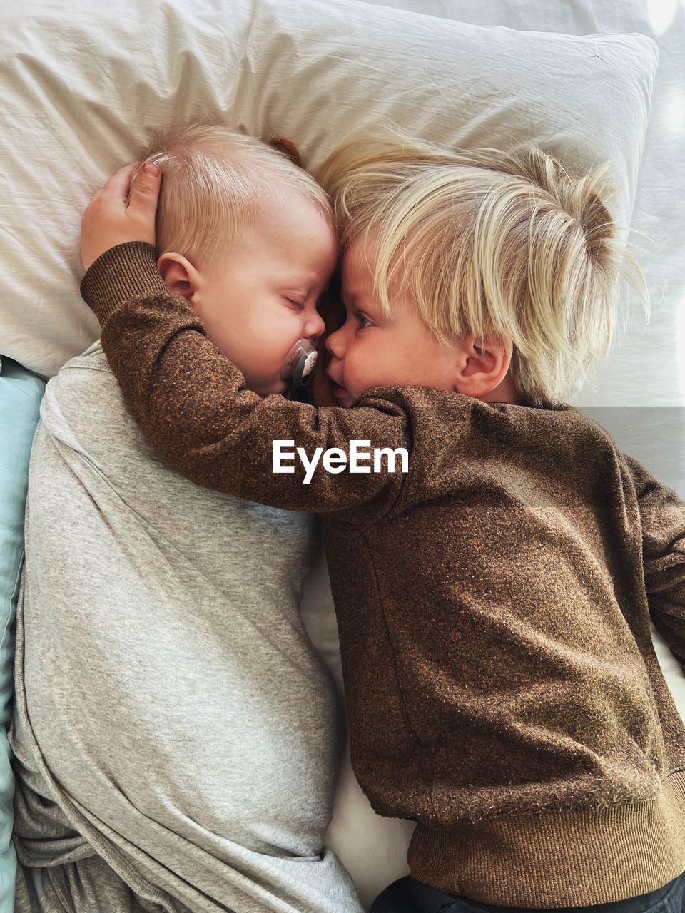 High angle view of two small children lying on bed at home