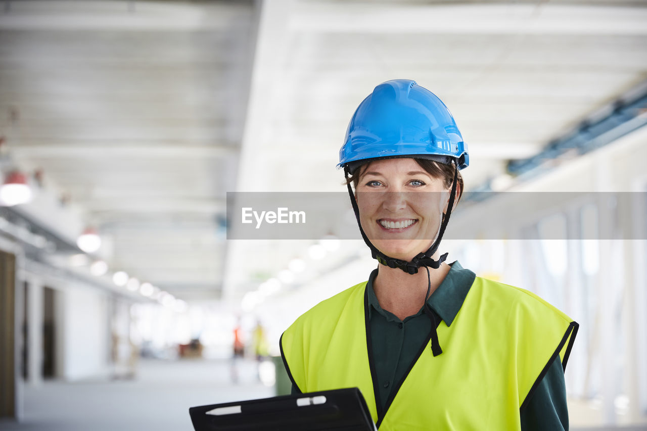 Portrait of smiling female construction manager in reflective clothing at site