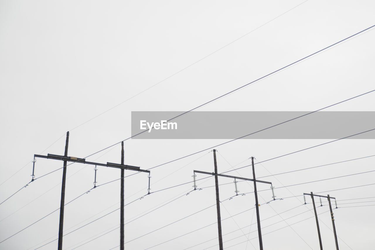 Low angle view of electricity pylons against clear sky