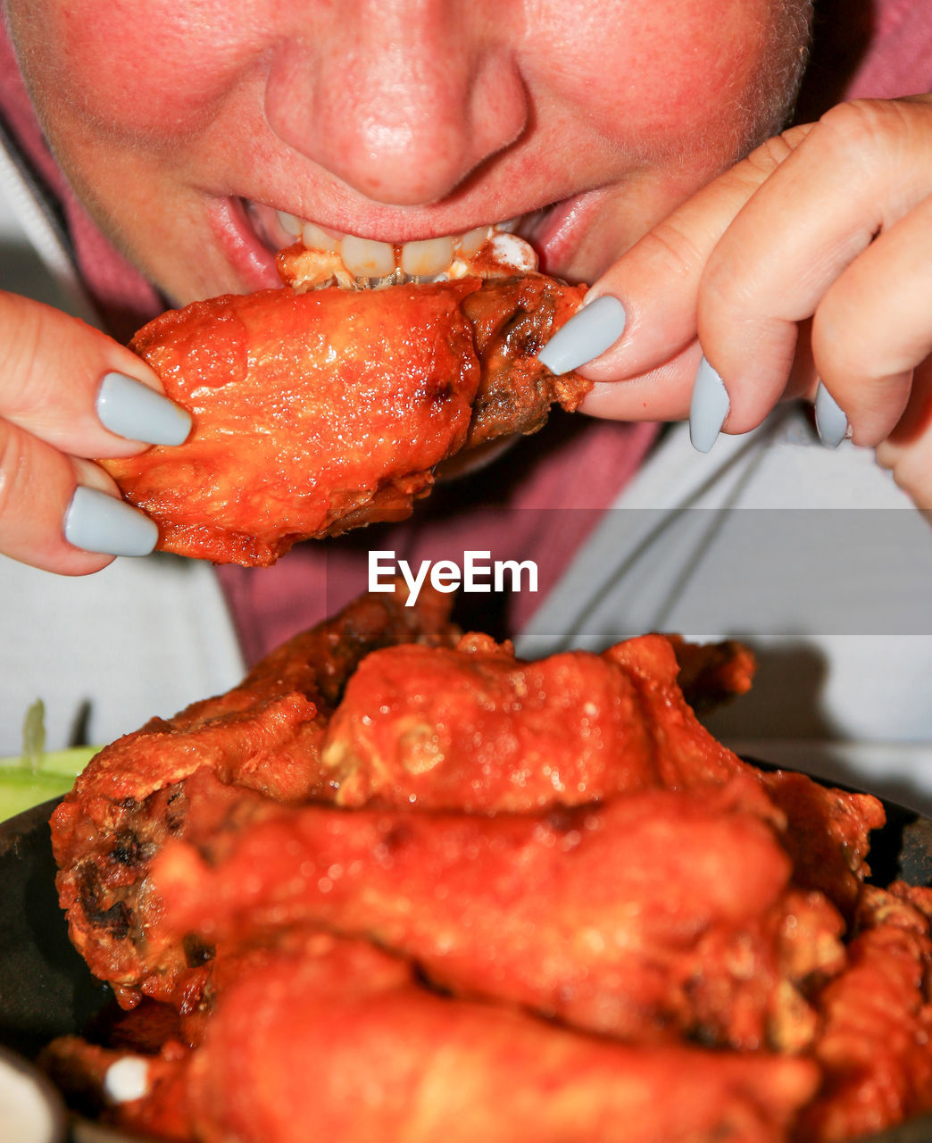 A close up of a person eating buffulo chicken wings. person