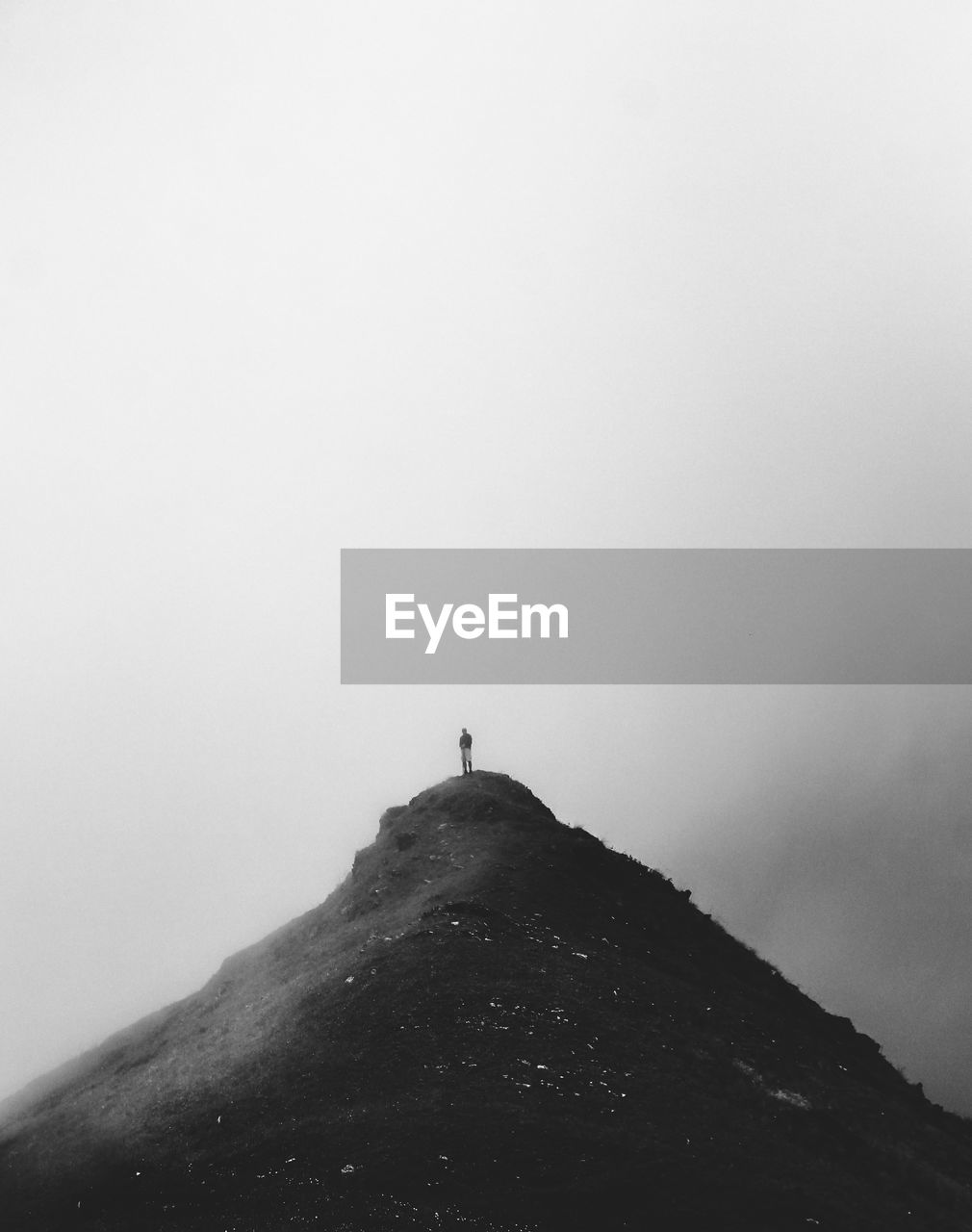 Person standing on mountain against sky during winter