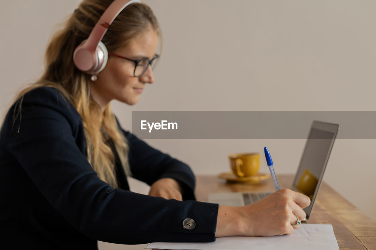 Woman working at home with laptop and papers on desk and headphones. home office . gray notebook 