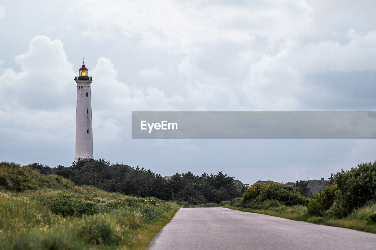 lighthouse by mountain against sky