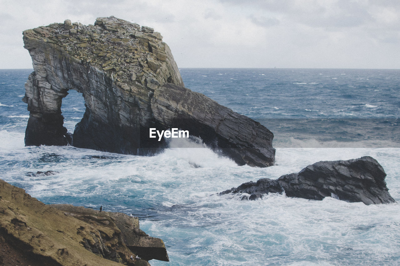 Rock formation in sea against sky