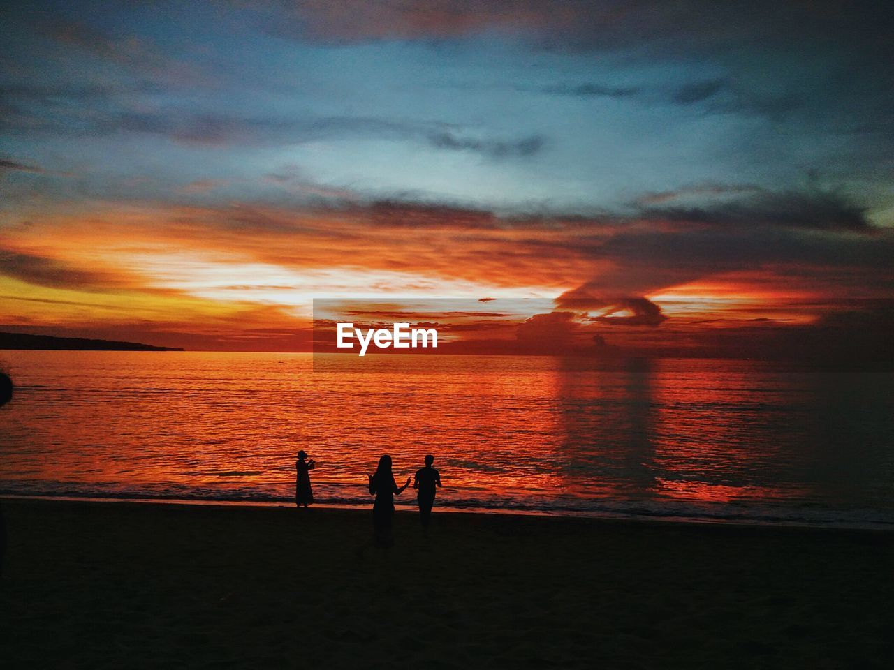 Silhouette people at beach against sky during sunset