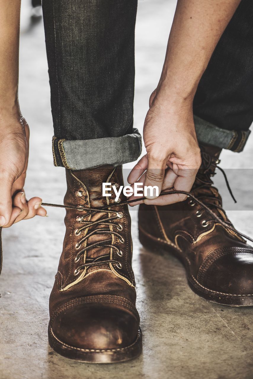 Low section of man tying shoelace