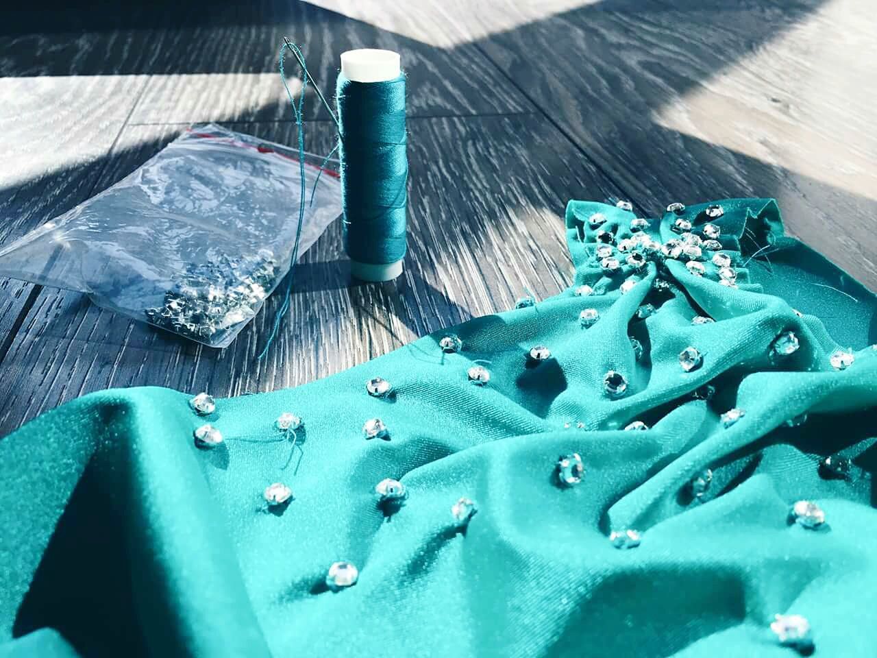 Diamonds on turquoise fabric by spool on wooden table