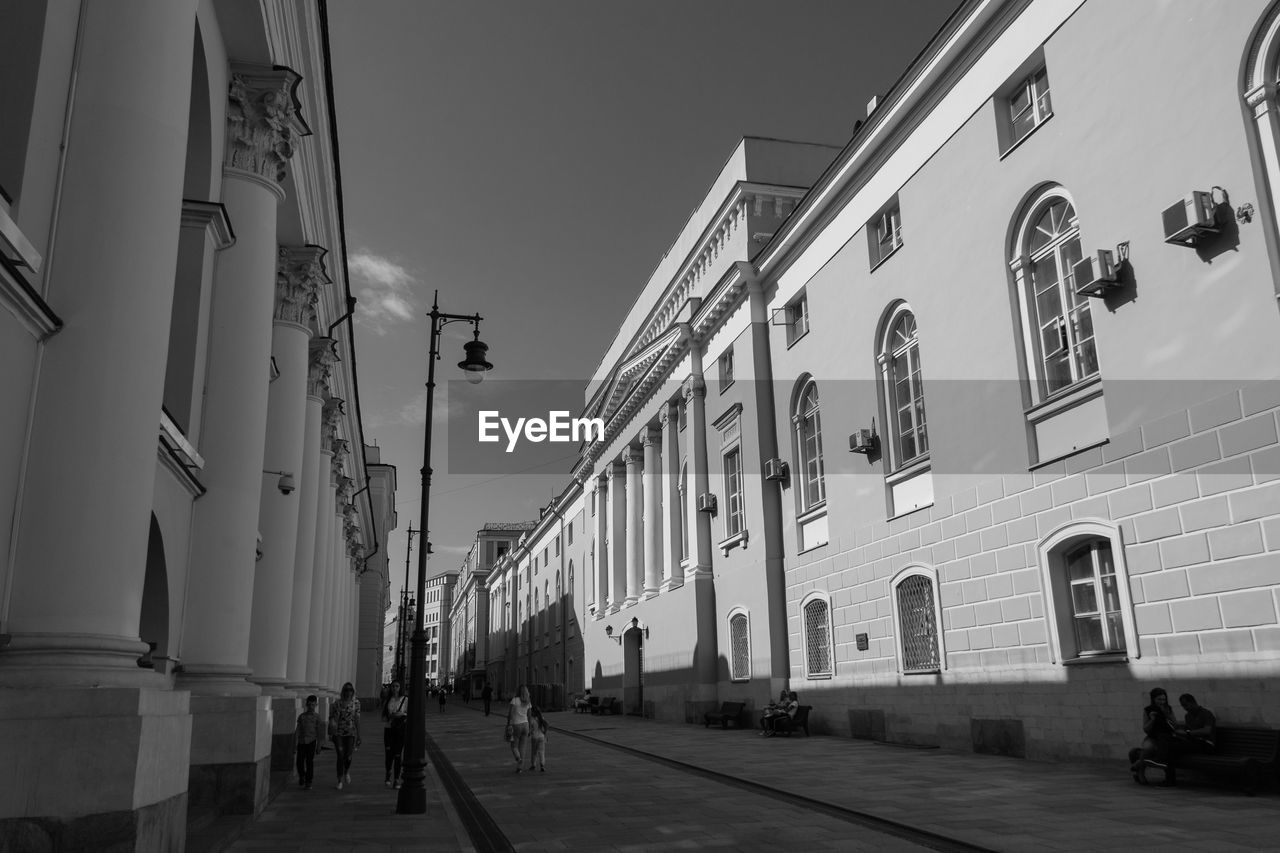 People walking on street amidst buildings against clear sky