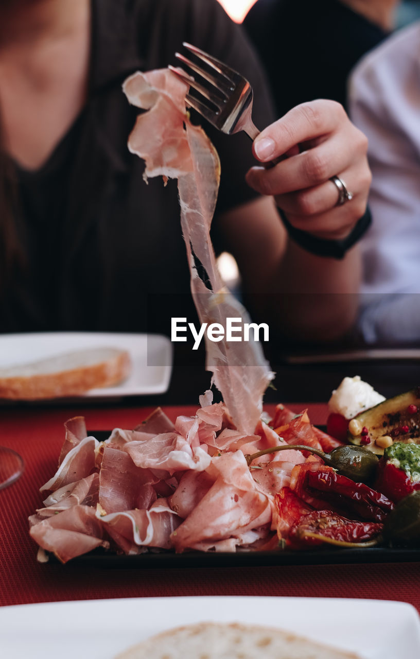 Close-up of person taking ham from a plate