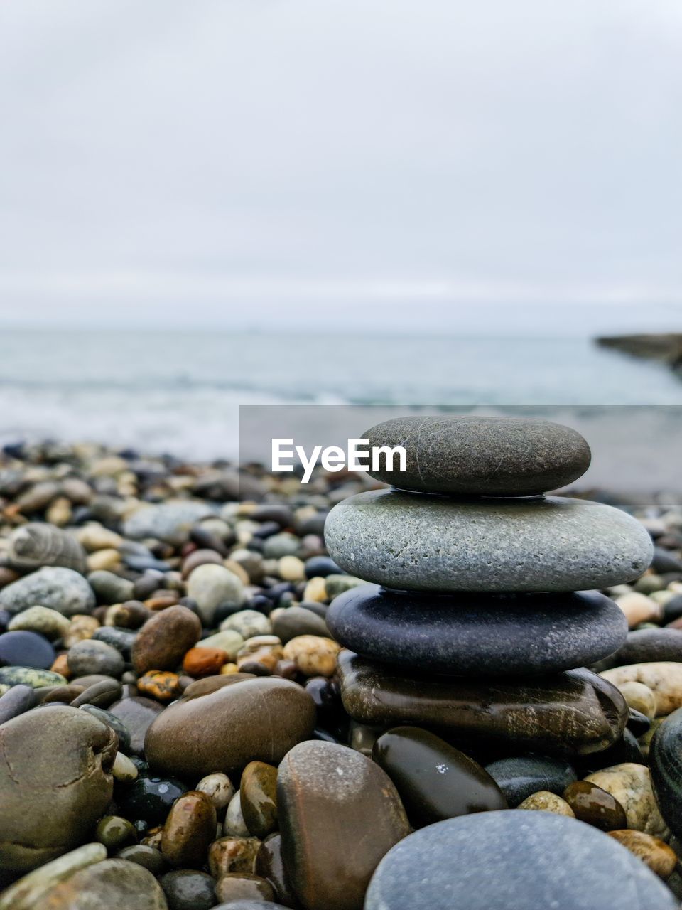 pebble, rock, shore, stone, sea, beach, water, land, nature, tranquility, beauty in nature, coast, zen-like, tranquil scene, sand, no people, sky, balance, day, horizon, horizon over water, scenics - nature, large group of objects, ocean, outdoors, focus on foreground, idyllic, abundance, body of water