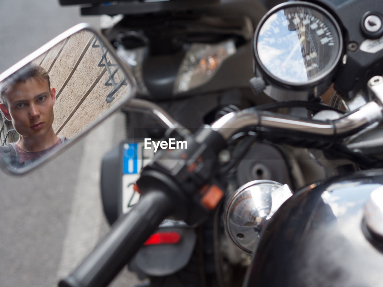 Portrait of man looking in motor cycle mirror