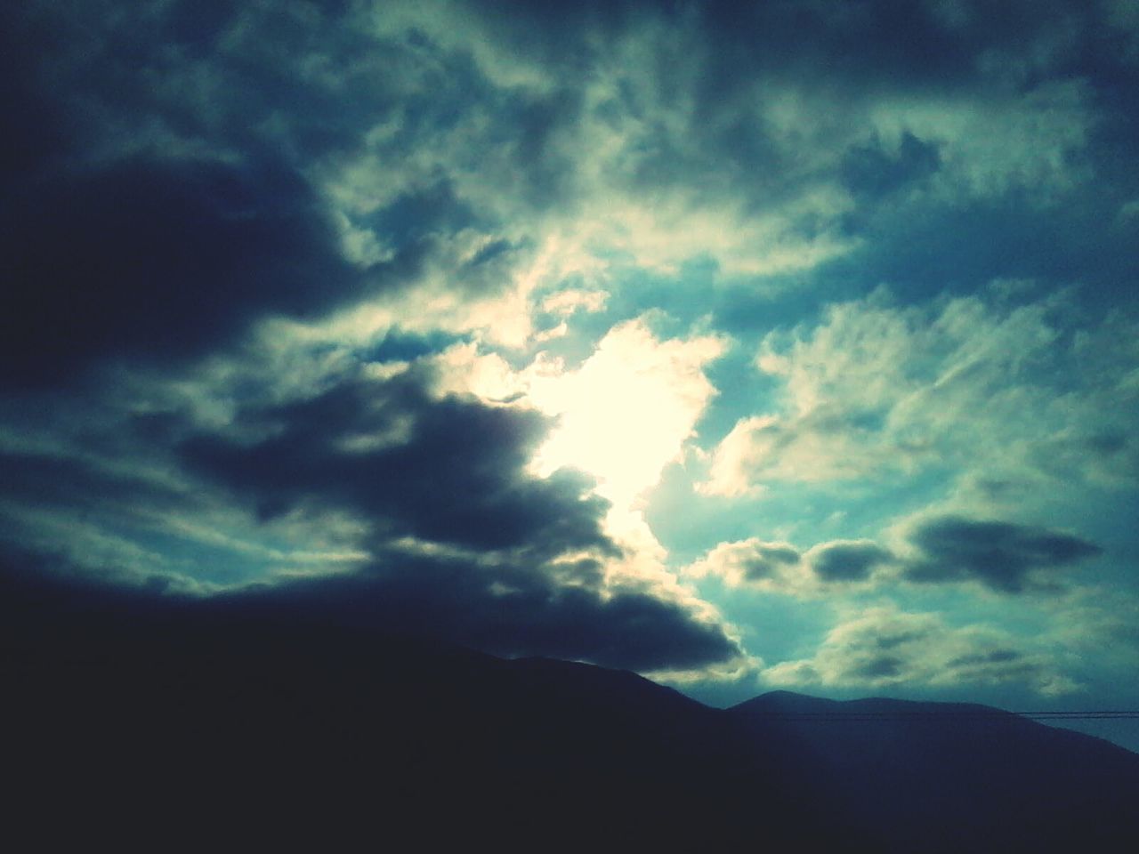 Silhouette landscape against cloudy sky